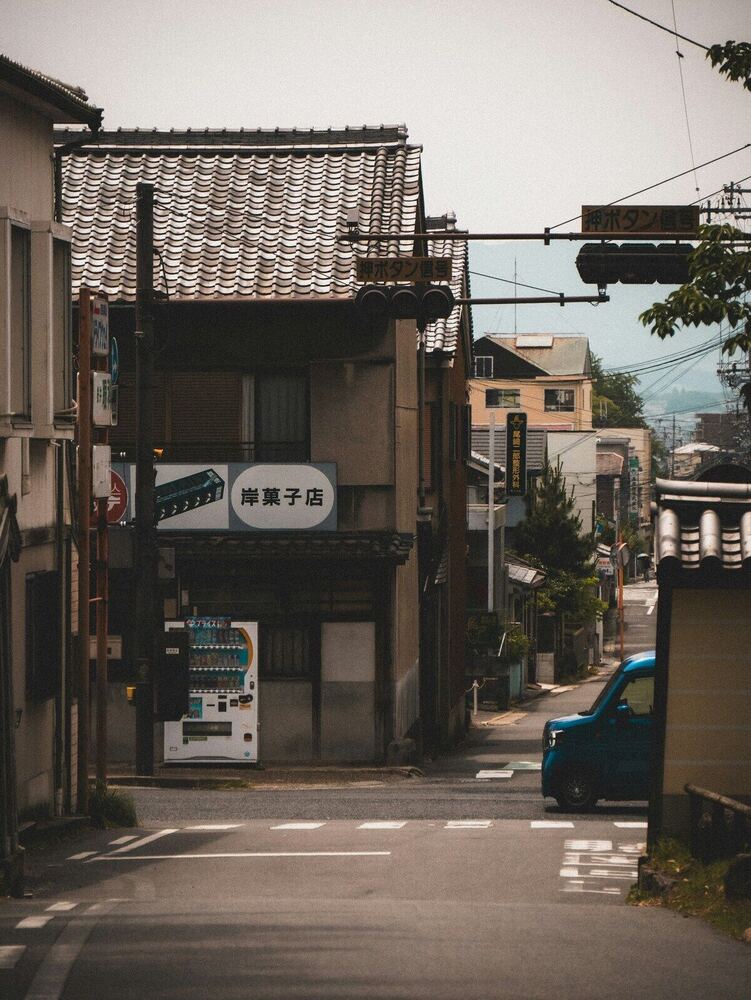日本の地方都市の通り。菓子店の看板と自販機が見える