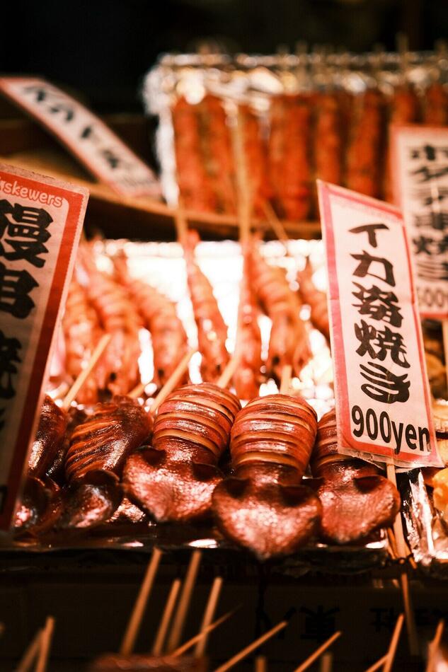 市場の屋台に並ぶ串焼き。手書きの値札が添えられている
